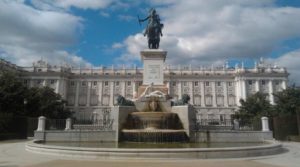 En la imagen se puede ver las dos fuentes que, situadas en el centro de la plaza, abrigan a la estatua ecuestre de Felipe IV, y que está considerada como la primera estatua ecuestre del mundo sujetada únicamente por las patas traseras del caballo. Al fondo, en la parte occidental, el Palacio Real.